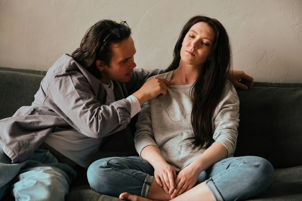 Man and woman on sofa. Woman is leaning away from man